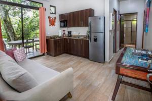 a kitchen with a couch and a refrigerator and a table at Hotel Casa del Arbol Manuel Antonio - Adults Only in Manuel Antonio