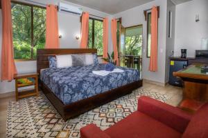 a bedroom with a bed and a couch and windows at Hotel Casa del Arbol Manuel Antonio - Adults Only in Manuel Antonio +50 photos