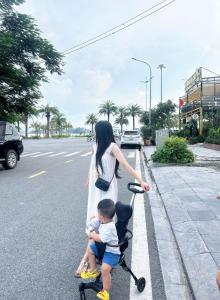 a woman and a child riding a scooter on the street at Sao Mai Hotel Hạ Long in Ha Long