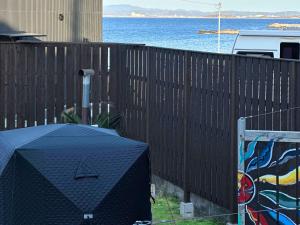 a black fence with a table in front of the water at Little Seagull by SANA in Tateyama