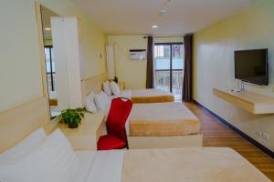 a hotel room with two beds and a television at Olive Town Center and Hotel in Baguio