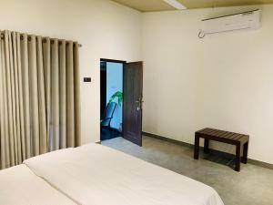 a bedroom with a bed and a door with a table at Elephant Trail Homestay in Habarana