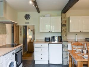 a large kitchen with white cabinets and a table at Rose Cottage - Uk34067 in Grassington