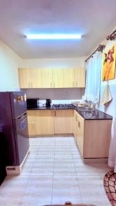 a kitchen with a black refrigerator and wooden cabinets at Polea Tatu in Ngong