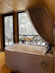 a bath tub in a room with a window at Forest view kazbegi in Sioni
