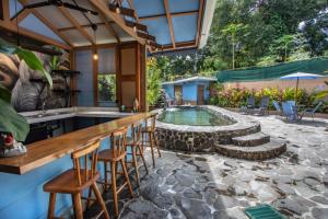 a patio with a bar and a swimming pool at Hotel Casa del Arbol Manuel Antonio - Adults Only in Manuel Antonio