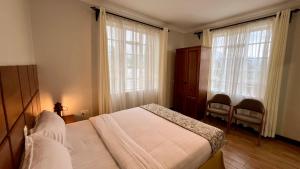 a bedroom with a bed and two large windows at Iwandaa Apartments in Nkoanrua