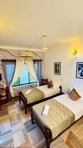 a hotel room with two beds and a window at Scarlets Inn in Cochin