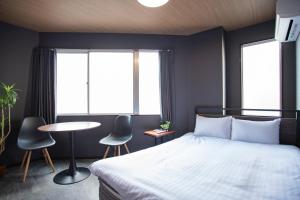 a bedroom with a bed and two chairs and a table at H-1ビル 301 hiroshima in Hiroshima