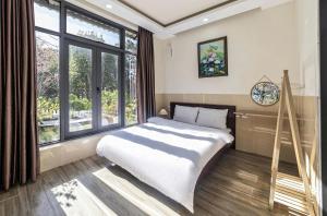 a bedroom with a large bed and a large window at Hamilton Villa Da Lat - Pine Tree n Valley View in Khu Chi Lăng