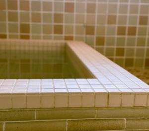 a bath tub in a bathroom with tiled walls at Yuzawa Hotel New Fukudaya-ski in ski out in Minami Uonuma