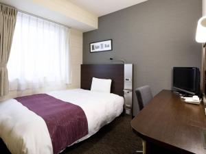 a hotel room with a bed and a desk and a television at Comfort Hotel Yamagata in Yamagata