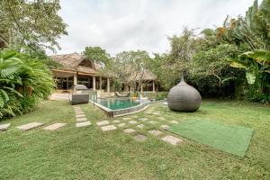 a backyard with a swimming pool and a house at Nomadic Resort Bali in Canggu