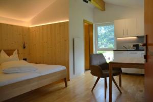 a bedroom with a bed and a desk and a kitchen at Ferienwohnung Davenna in Vandans