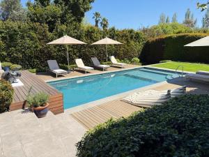 a swimming pool with chairs and umbrellas in a yard at Le Bas De Laine in Franschhoek