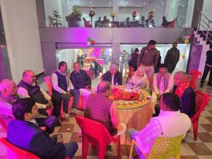 a group of people sitting around a table with a cake at GeetKamal Palace Ayodhya Dham in Ayodhya