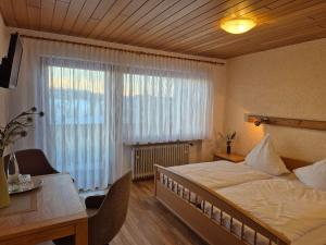 a bedroom with a bed and a desk and a window at Gasthof Siebenstern in Röslau
