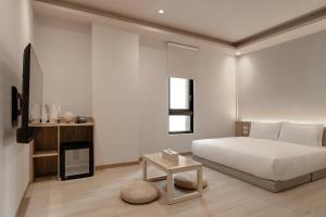 a white bedroom with a bed and a table at HOYU INN's in T'ien-liao