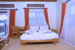 a bedroom with a large bed with orange curtains at Hakyiri B&B in Kabale +131 photos