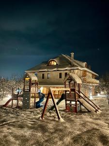 a playground in front of a house at night at Pensiunea Coronita in Vişeu de Sus