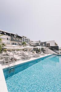 a swimming pool with white lounge chairs and a hotel at Padam Hotel & SPA in Ulcinj