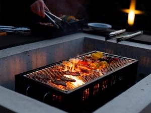 a grill with meat and vegetables cooking on it at The THERM in Munakata