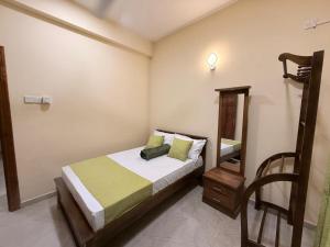 a bedroom with a bed and a mirror and a chair at Wellness Residencies in Colombo