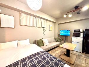 a bedroom with a bed and a couch and a tv at Hal Kokubunji in Kokubunji