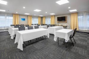 a conference room with white tables and chairs and a tv at Quality Suites in Drummondville +65 photos