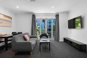 a living room with a couch and a tv at Comfort Apartments Melbourne Central in Melbourne