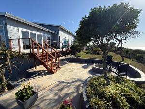 a house with a deck and a patio with a bench at Huis Seenekal in Cannon Rocks
