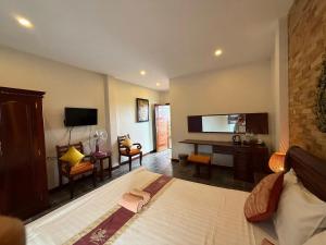 a bedroom with a bed and a desk and a television at Sunset View Guest House in Siem Reap
