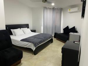 a bedroom with a bed and a couch and a chair at Hotel Tariq Monteria in Montería