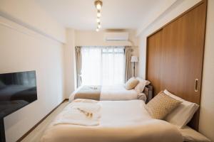 a hotel room with two beds and a window at Roots Osaka Station 2 in Osaka