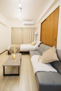 a living room with two beds and a couch at Roots Osaka Station 2 in Osaka