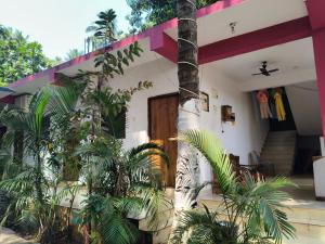 a house with palm trees in front of it at R K Guest House Arpora in Mapusa