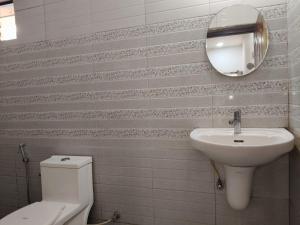 a bathroom with a sink and a toilet and a mirror at R K Guest House Arpora in Mapusa