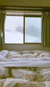 an unmade bed in a room with a window at Yuzawa Hotel New Fukudaya-ski in ski out in Minami Uonuma +34 photos