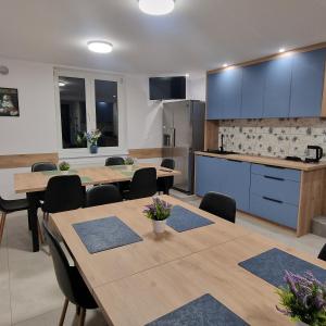 a kitchen and dining room with wooden tables and chairs at Willa Na Białej in Ziajki