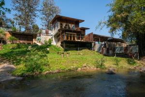 a house on top of a hill next to a river at Cozy Home Saluang in Ban Lua Ka