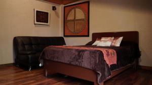 a bedroom with a bed and a leather chair at Hotel Coyoacan in Mexico City