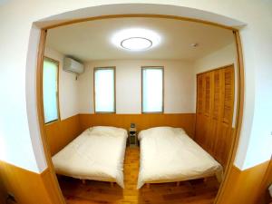 two beds in a small room with two windows at CARA-YA(かーらやー） in Ishigaki Island