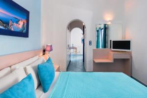1 dormitorio con 1 cama con almohadas azules y TV en Samson΄s Village, en Perissa