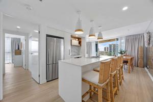 a kitchen and dining room with a white counter and chairs at Stylish Beachside Retreat in Gold Coast