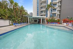 a large swimming pool with chairs and a building at Stylish Beachside Retreat in Gold Coast