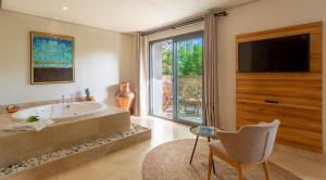 a bathroom with a tub and a tv and a chair at Ecclesia Hotel - Adult Only (+14) in Oludeniz