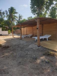 a wooden pavilion with two benches under a canopy at Newdarling beach hotel in Watamu +7 photos