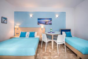 two beds in a room with a table and chairs at Samson΄s Village in Perissa
