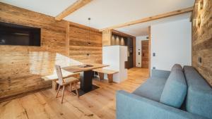 a living room with a blue couch and a wooden wall at Kuenzerhof Apartments in Braies