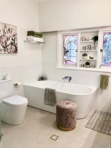 a white bathroom with a tub and a toilet at Hills Manor House in Greenmount +30 photos